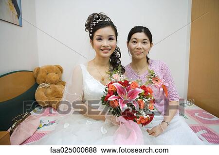 Bride sitting on bed beside bridesmaid, smiling at camera View Large Photo Image Stock Photo - Bride sitting on bed beside bridesmaid, smiling at camera. Fotosearch