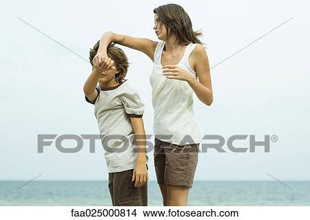 Picture - Brother and sister at the beach, holding hands, looking at view. Fotosearch