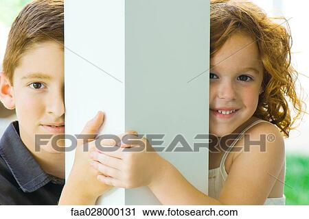 Brother and sister peeking around column at camera, holding hands, smiling View Large Photo Image Stock Image - Brother and sister peeking around column at camera, holding hands, smiling. Fotosearch