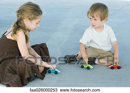 Brother and sister sitting on the ground, playing with toy cars, boy frowning at girl View Large Photo Image Stock Image - Brother and sister sitting on the ground, playing with toy cars, boy frowning at girl. Fotosearch