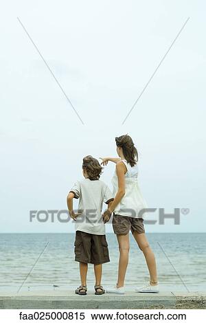 Brother and sister standing at the beach holding hands, pointing at view View Large Photo Image Stock Photography - Brother and sister standing at the beach holding hands, pointing at view. Fotosearch