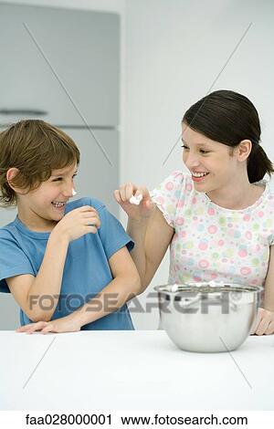 Brother and sister standing in kitchen, girl putting whipped cream on boy's nose, both smiling View Large Photo Image Stock Image - Brother and sister standing in kitchen, girl putting whipped cream on boy's nose, both smiling. Fotosearch