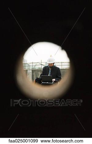 Building contractor working at construction site, seen through hole View Large Photo Image Stock Photo - Building contractor working at construction site, seen through hole. Fotosearch