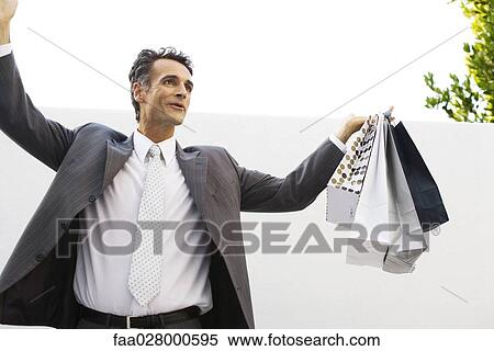 Businessman holding shopping bags, arms raised View Large Photo Image Stock Photography - Businessman holding shopping bags, arms raised. Fotosearch