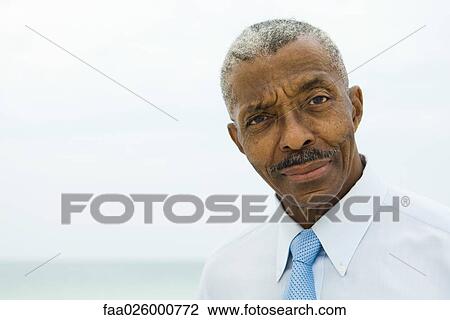 Businessman, looking at camera, sea in background View Large Photo Image Stock Image - Businessman, looking at camera, sea in background. Fotosearch