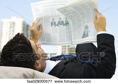 Stock Photo - Businessman lounging outdoors, reading newspaper. Fotosearch