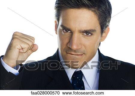 Stock Image - Businessman making fist and biting lip, looking at camera. Fotosearch