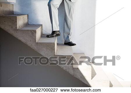Businessman standing on staircase, low section, low angle view View Large Photo Image Stock Photo - Businessman standing on staircase, low section, low angle view. Fotosearch