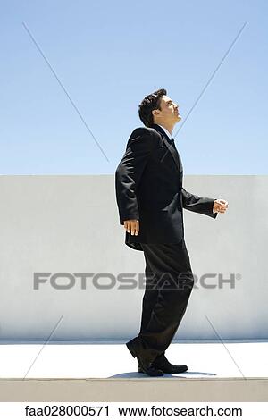 Businessman standing outdoors with one knee bent, looking up View Large Photo Image Stock Image - Businessman standing outdoors with one knee bent, looking up. Fotosearch