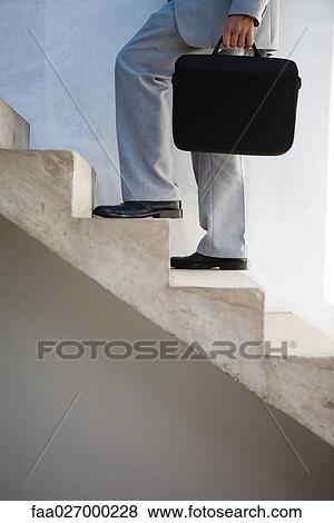 Businessman walking up steps, carrying briefcase, side view, cropped View Large Photo Image Stock Photo - Businessman walking up steps, carrying briefcase, side view, cropped. Fotosearch