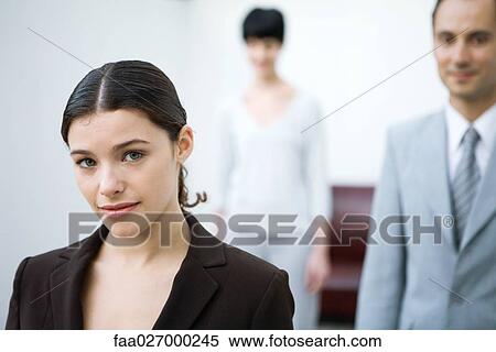 Stock Photography - Businesswoman smiling at camera, colleagues in background. Fotosearch
