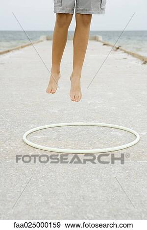 Child jumping in the air over plastic hoop, cropped view of legs View Large Photo Image Stock Photo - Child jumping in the air over plastic hoop, cropped view of legs. Fotosearch