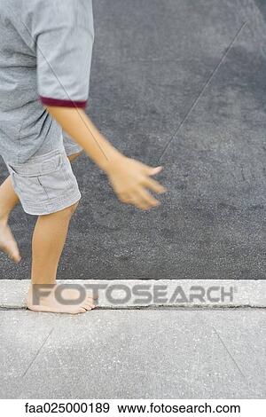 Child walking along crack in sidewalk, cropped view View Large Photo Image Stock Photo - Child walking along crack in sidewalk, cropped view. Fotosearch