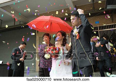 Chinese wedding, bride and groom leaving under confetti, bride covered by red parasol View Large Photo Image Stock Image - Chinese wedding, bride and groom leaving under confetti, bride covered by red parasol. Fotosearch
