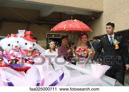 Chinese wedding, bride and groom leaving under confetti, bride covered by red parasol, decorated car in foreground View Large Photo Image Stock Image - Chinese wedding, bride and groom leaving under confetti, bride covered by red parasol, decorated car in foreground. Fotosearch