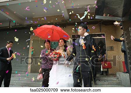 Chinese wedding, bride and groom leaving under confetti, bride covered by red parasol View Large Photo Image Stock Photo - Chinese wedding, bride and groom leaving under confetti, bride covered by red parasol. Fotosearch
