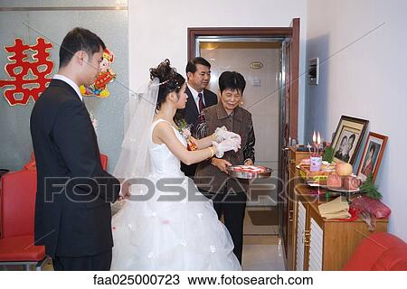 Stock Image - Chinese wedding, bride taking offering to ancestral shrine. Fotosearch