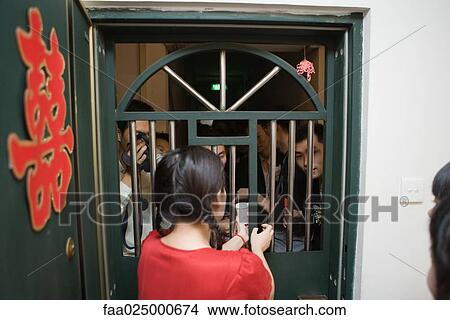 Chinese wedding door tradition, female handing cup to group of men through barred door, rear view View Large Photo Image Picture - Chinese wedding door tradition, female handing cup to group of men through barred door, rear view. Fotosearch