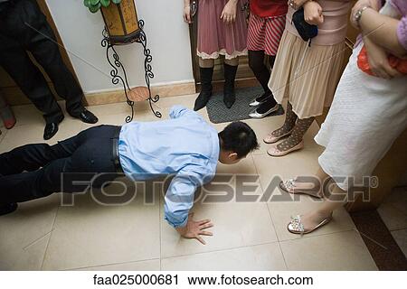 Stock Image - Chinese wedding, groom doing push-ups while women watch. Fotosearch