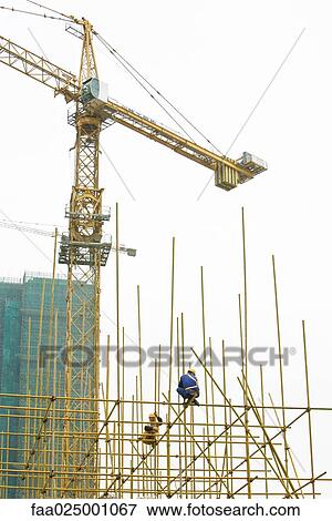 Stock Photo - Construction site, workers perched on metal framework. Fotosearch