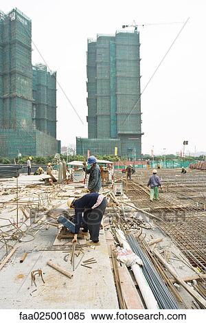 Stock Photography - Construction workers working at construction site. Fotosearch