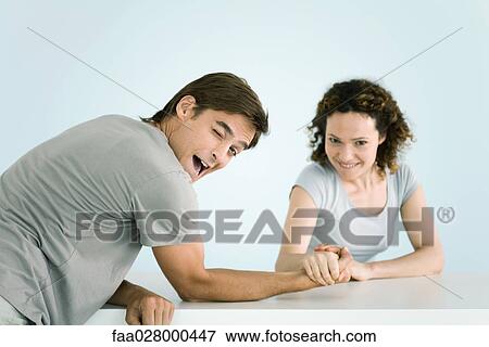 Couple arm wrestling, both looking at camera, man winking as he lets woman win View Large Photo Image Stock Photo - Couple arm wrestling, both looking at camera, man winking as he lets woman win. Fotosearch