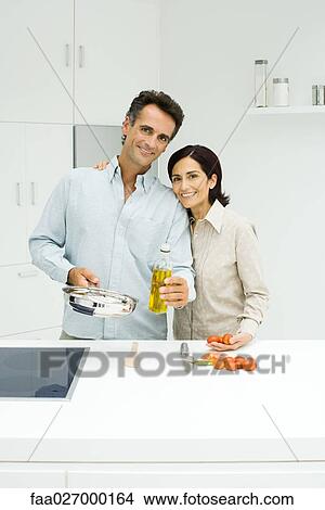 Couple cooking together in kitchen, both smiling at camera View Large Photo Image Picture - Couple cooking together in kitchen, both smiling at camera. Fotosearch