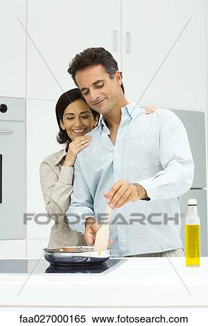 Couple cooking together in kitchen, woman leaning head on man's shoulder, both looking down View Large Photo Image Stock Photography - Couple cooking together in kitchen, woman leaning head on man's shoulder, both looking down. Fotosearch
