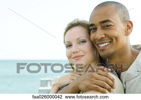 Couple embracing outdoors, smiling at camera together View Large Photo Image Stock Image - Couple embracing outdoors, smiling at camera together. Fotosearch