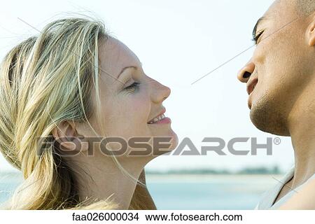 Couple face to face, smiling at each other, side view View Large Photo Image Picture - Couple face to face, smiling at each other, side view. Fotosearch