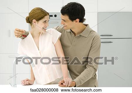 Couple holding hands in kitchen, smiling at each other, man holding cherries View Large Photo Image Stock Photo - Couple holding hands in kitchen, smiling at each other, man holding cherries. Fotosearch
