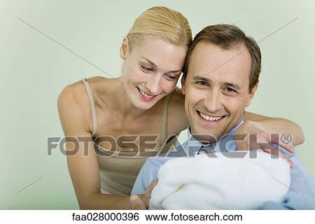 Couple holding new baby wrapped in blanket, smiling, man looking at camera View Large Photo Image Stock Photograph - Couple holding new baby wrapped in blanket, smiling, man looking at camera. Fotosearch