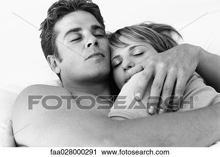 Stock Image - Couple reclining, embracing, eyes closed, close-up. Fotosearch