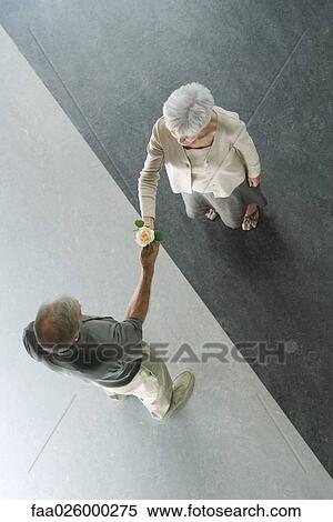 Couple standing on divided black and white floor, man handing woman rose, viewed from directly above View Large Photo Image Stock Photography - Couple standing on divided black and white floor, man handing woman rose, viewed from directly above. Fotosearch