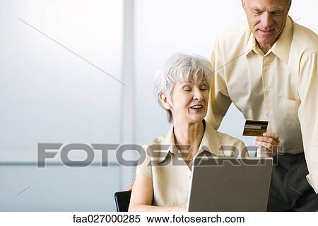 Couple using laptop computer, woman holding up credit card View Large Photo Image Stock Photography - Couple using laptop computer, woman holding up credit card. Fotosearch