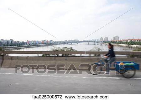 Cyclist with cart crossing bridge, blurred motion View Large Photo Image Stock Image - Cyclist with cart crossing bridge, blurred motion. Fotosearch