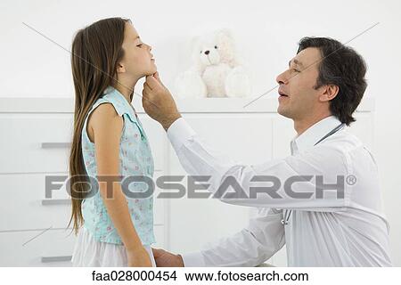Doctor crouching, examining little girl, side view View Large Photo Image Picture - Doctor crouching, examining little girl, side view. Fotosearch