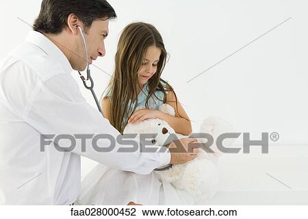 Doctor sitting with little girl, examining teddy bear with stethoscope View Large Photo Image Stock Image - Doctor sitting with little girl, examining teddy bear with stethoscope. Fotosearch