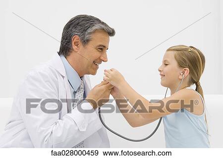 Doctor talking into stethoscope as little girl listens, both smiling View Large Photo Image Stock Photo - Doctor talking into stethoscope as little girl listens, both smiling. Fotosearch