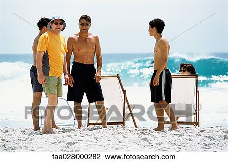 Family at the beach, chatting, two men looking at camera View Large Photo Image Stock Image - Family at the beach, chatting, two men looking at camera. Fotosearch