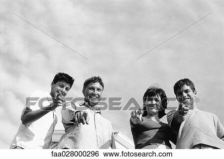 Family standing together outdoors, pointing and smiling at camera, low angle view View Large Photo Image Stock Photograph - Family standing together outdoors, pointing and smiling at camera, low angle view. Fotosearch
