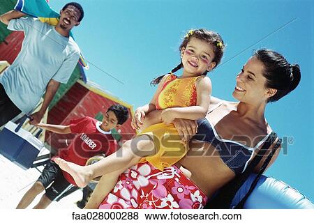 Family walking at the beach, mother carrying daughter, girl smiling at camera View Large Photo Image Stock Photo - Family walking at the beach, mother carrying daughter, girl smiling at camera. Fotosearch