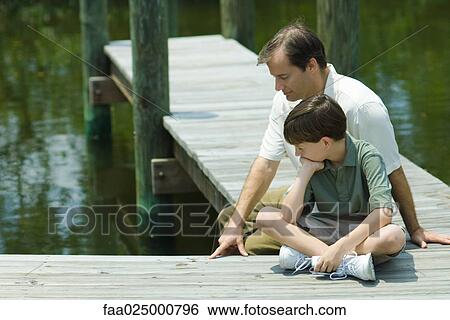 Father and son sitting on dock, looking down together View Large Photo Image Stock Photograph - Father and son sitting on dock, looking down together. Fotosearch