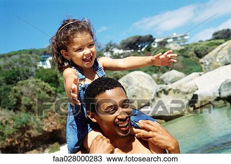 Father carrying daughter on shoulders at the beach, both smiling, close-up View Large Photo Image Stock Image - Father carrying daughter on shoulders at the beach, both smiling, close-up. Fotosearch