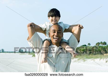 Father carrying son on shoulders, both smiling at camera View Large Photo Image Stock Photo - Father carrying son on shoulders, both smiling at camera. Fotosearch