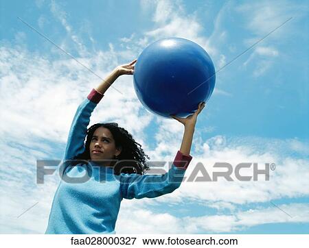 Female holding ball outdoors, arms raised, low angle view View Large Photo Image Stock Photo - Female holding ball outdoors, arms raised, low angle view. Fotosearch