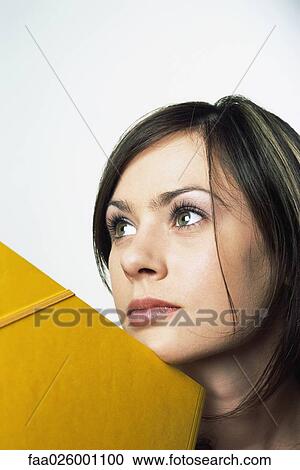 Female leaning chin against folder, looking up, close-up View Large Photo Image Stock Image - Female leaning chin against folder, looking up, close-up. Fotosearch