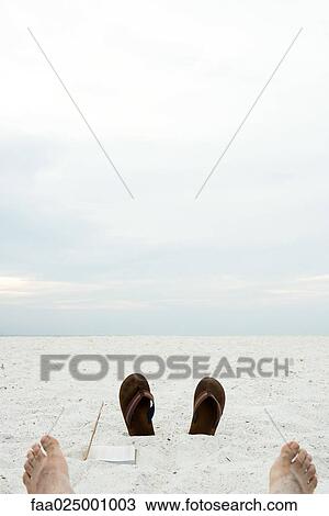 Flipflops sticking out of sand, bare feet in foreground View Large Photo Image Stock Image - Flipflops sticking out of sand, bare feet in foreground. Fotosearch