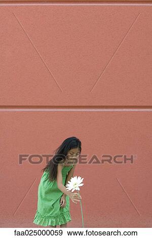 Stock Photo - Girl bending over to pick tall flower. Fotosearch