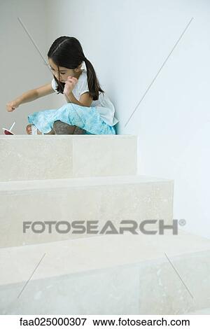 Girl sitting on steps playing with top, low angle view View Large Photo Image Stock Photo - Girl sitting on steps playing with top, low angle view. Fotosearch